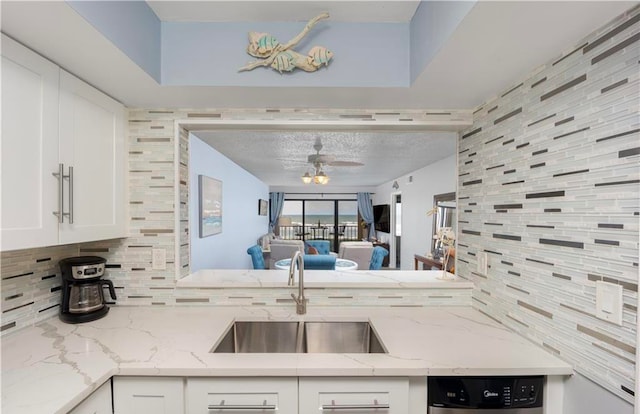 kitchen with sink, white cabinetry, light stone counters, and backsplash