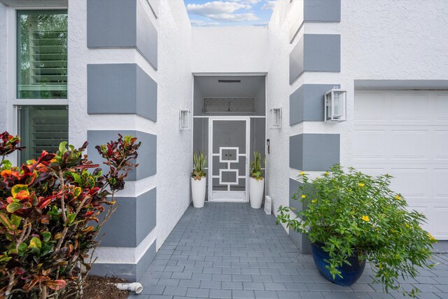 entrance to property featuring a garage and stucco siding