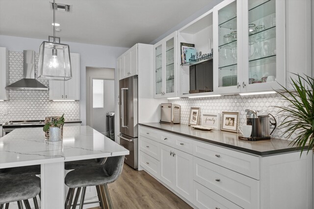 kitchen featuring visible vents, wall chimney range hood, appliances with stainless steel finishes, and white cabinetry