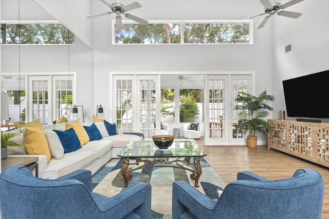 living area featuring plenty of natural light, wood finished floors, visible vents, and a ceiling fan