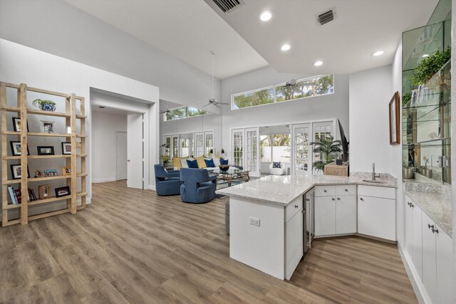 kitchen with visible vents, white cabinets, wood finished floors, a peninsula, and french doors