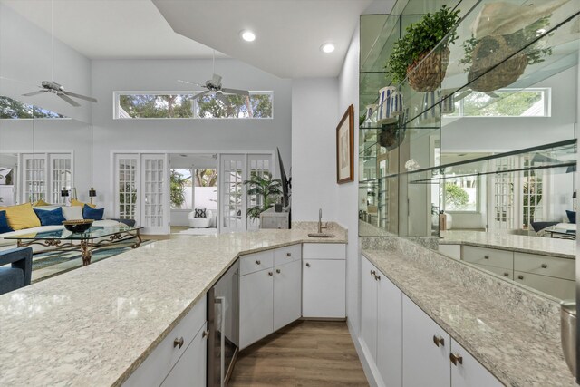 kitchen with wine cooler, french doors, a high ceiling, open floor plan, and wood finished floors