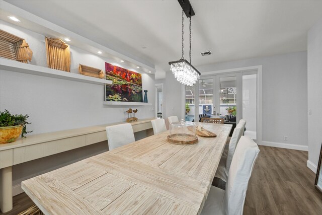 dining room with a notable chandelier, recessed lighting, wood finished floors, visible vents, and baseboards