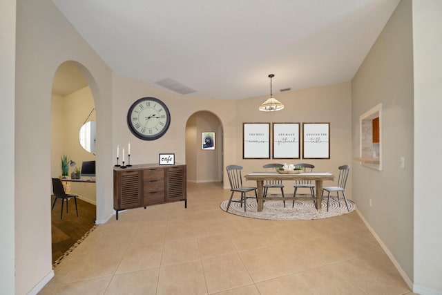 dining space with arched walkways, visible vents, baseboards, and light tile patterned floors