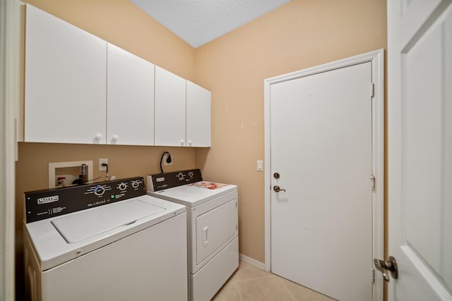 clothes washing area featuring washer and clothes dryer, light tile patterned floors, cabinet space, a textured ceiling, and baseboards