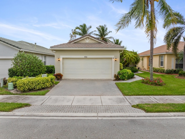 single story home with an attached garage, a tiled roof, decorative driveway, stucco siding, and a front yard