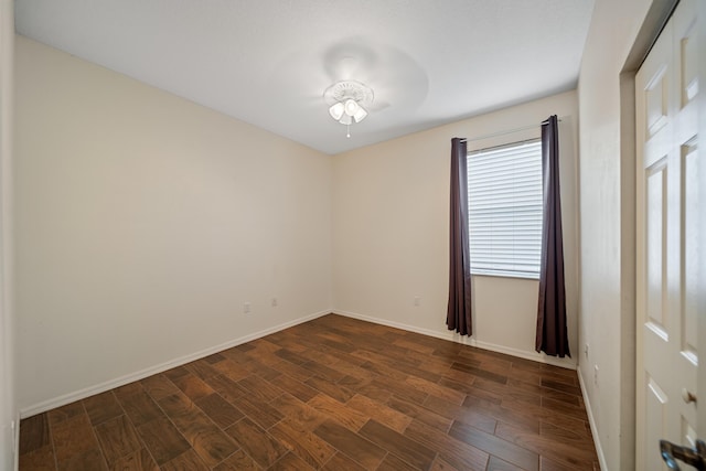 spare room with ceiling fan, dark wood-style flooring, and baseboards