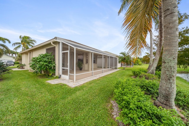 exterior space featuring stucco siding, a sunroom, and a yard