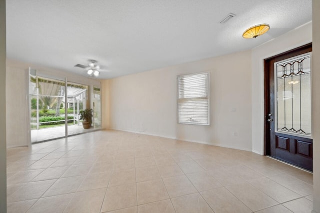 unfurnished room with light tile patterned floors, visible vents, baseboards, and a textured ceiling