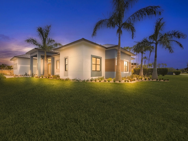 property exterior at dusk featuring a lawn