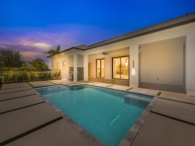 pool at dusk with a patio area and ceiling fan