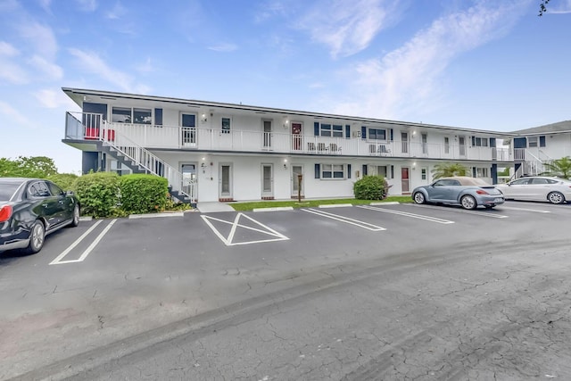 view of property featuring stairs and uncovered parking