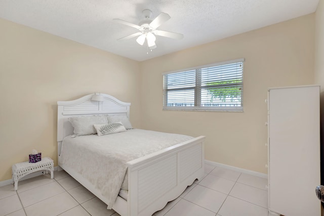 bedroom featuring a ceiling fan, baseboards, light tile patterned floors, and a textured ceiling