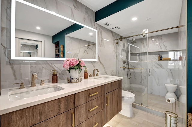 bathroom featuring vanity, toilet, tile walls, and a shower with shower door