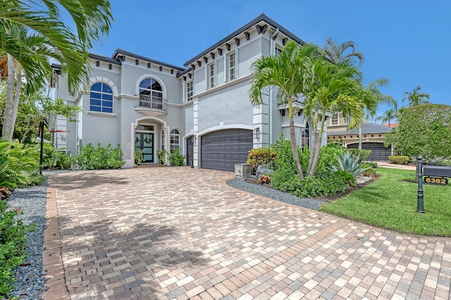 mediterranean / spanish house featuring a balcony, central AC, a garage, and a front lawn