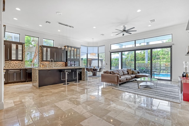 living room with crown molding, plenty of natural light, and ceiling fan