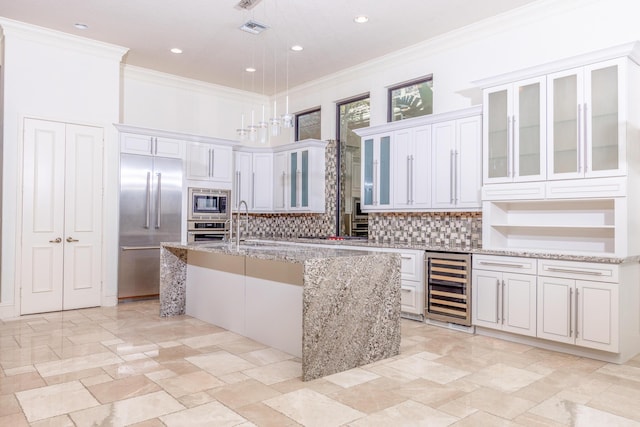 kitchen with white cabinetry, an island with sink, built in appliances, and wine cooler