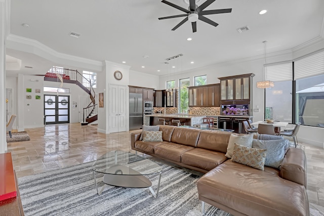 living room featuring ornamental molding, ceiling fan with notable chandelier, and a wealth of natural light