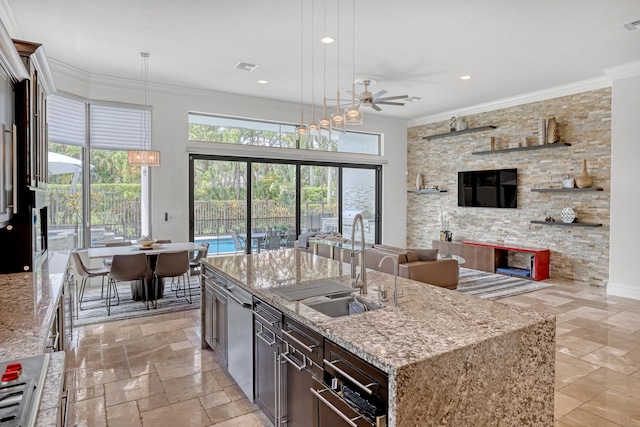 kitchen with crown molding, sink, a kitchen island with sink, and decorative light fixtures