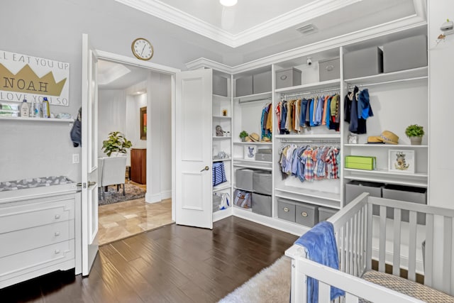 bedroom featuring dark hardwood / wood-style floors, ornamental molding, a closet, and a nursery area