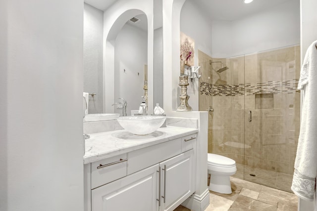 bathroom featuring vanity, a shower with shower door, and toilet