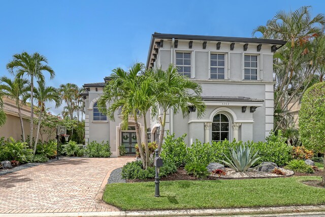 view of front facade with french doors, stucco siding, and decorative driveway