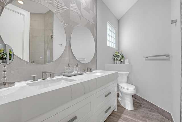 bathroom with vaulted ceiling, a shower, backsplash, vanity, and toilet