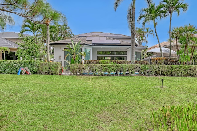 rear view of property with solar panels and a yard