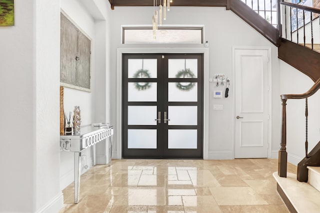 foyer with stairway, baseboards, french doors, and stone tile flooring