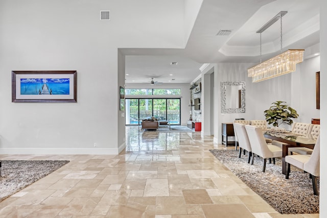 interior space with a tray ceiling and ceiling fan with notable chandelier