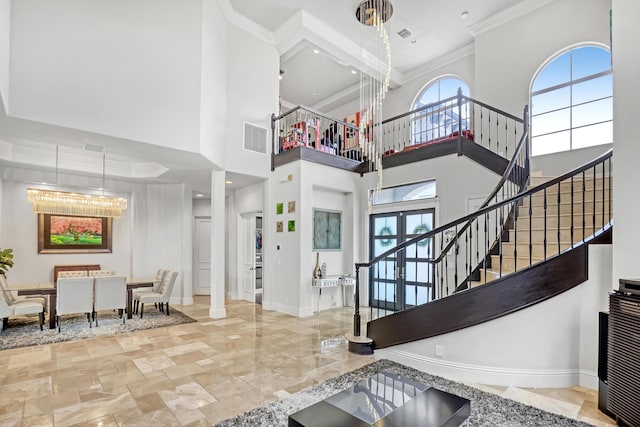 foyer with visible vents, ornamental molding, a high ceiling, and stairway