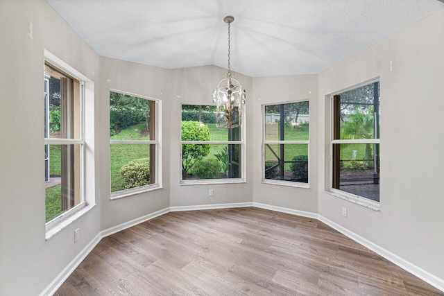 interior space with a notable chandelier, baseboards, wood finished floors, and a healthy amount of sunlight