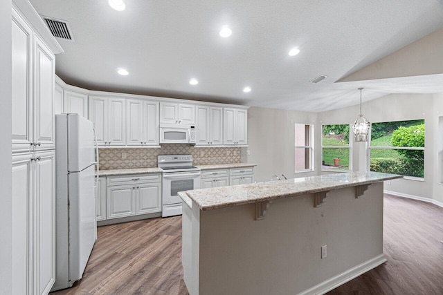 kitchen with lofted ceiling, light hardwood / wood-style flooring, a kitchen bar, white cabinets, and white appliances