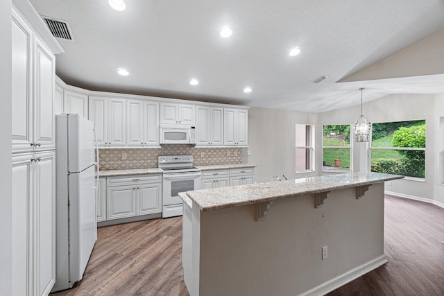kitchen featuring a breakfast bar area, light wood-style floors, white appliances, and white cabinets