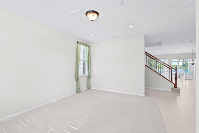 carpeted empty room with a chandelier