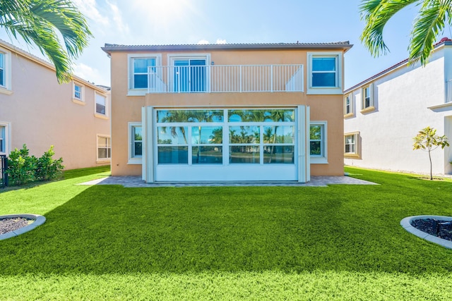 back of house with a balcony and a yard