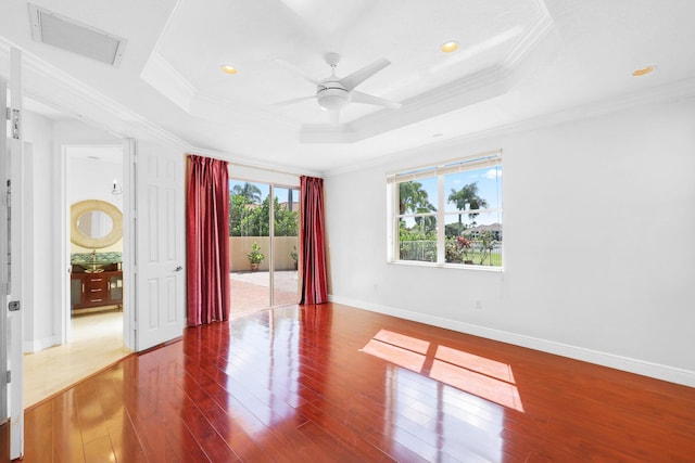 spare room featuring wood-type flooring, a tray ceiling, ceiling fan, and ornamental molding