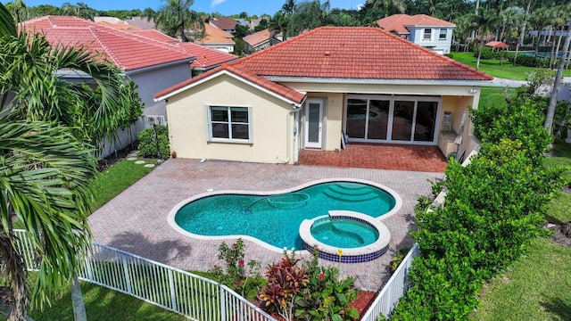 rear view of house with a swimming pool with hot tub and a patio