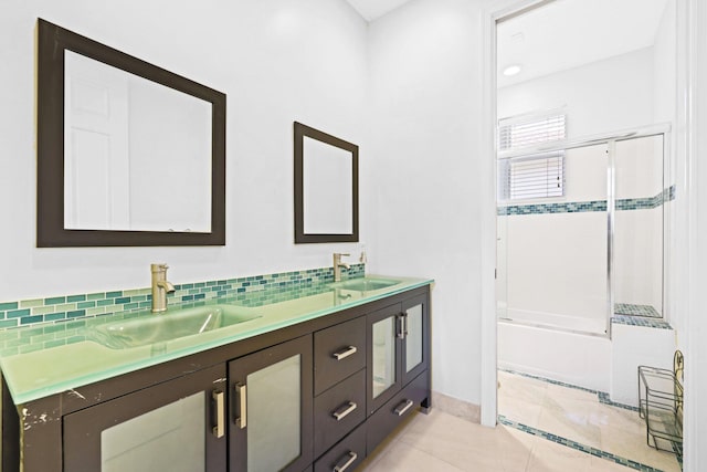 bathroom with tile patterned flooring, vanity, bath / shower combo with glass door, and backsplash