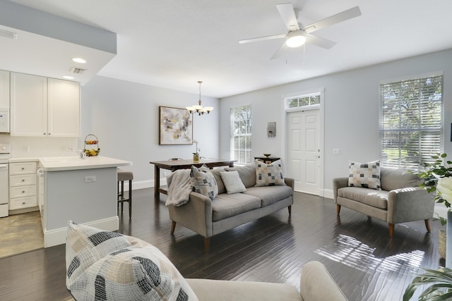 living room featuring ceiling fan with notable chandelier and dark wood-type flooring