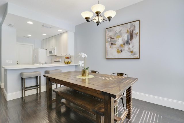 dining space featuring dark hardwood / wood-style floors and an inviting chandelier