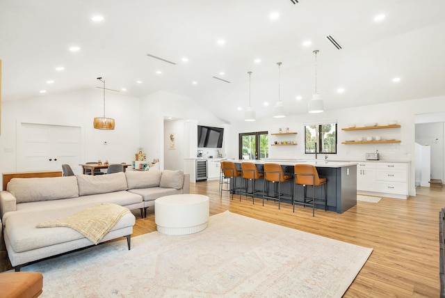 living room with wine cooler, high vaulted ceiling, and light wood-type flooring