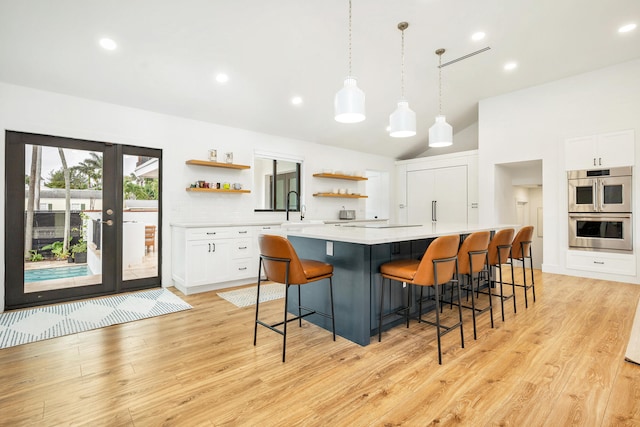 kitchen featuring french doors, a kitchen island, pendant lighting, white cabinetry, and light hardwood / wood-style floors