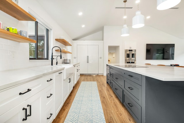 kitchen featuring white cabinetry, light wood-type flooring, vaulted ceiling, pendant lighting, and double oven