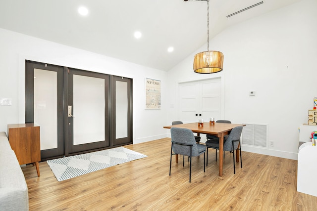 dining area with light hardwood / wood-style flooring and high vaulted ceiling