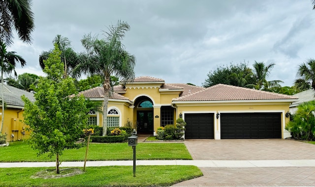 mediterranean / spanish home with a front lawn and a garage