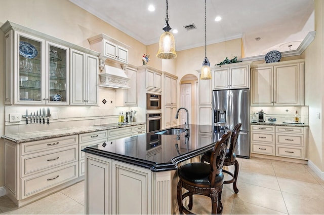 kitchen featuring a center island with sink, sink, pendant lighting, cream cabinetry, and stainless steel appliances