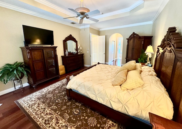 bedroom with dark hardwood / wood-style flooring, ornamental molding, a raised ceiling, and ceiling fan