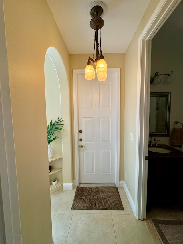 tiled foyer featuring a notable chandelier and sink