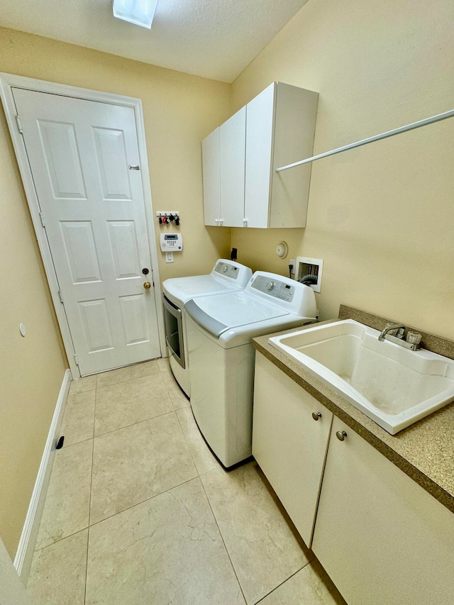 laundry area with sink, independent washer and dryer, a textured ceiling, and cabinets